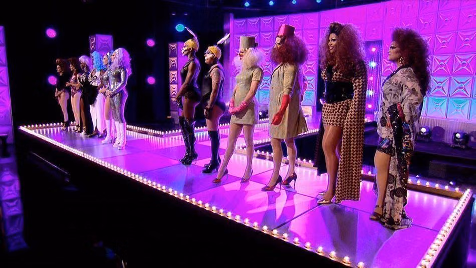 Season 9 queens and the crew members they made over, lined up on the main stage in matching looks