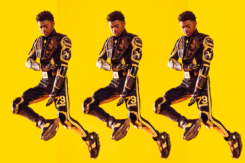 Lil Nas X shown three times mid-jump against a yellow background, wearing a black and gold motocross-style suit
