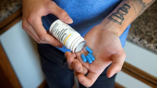 Man pouring blue Truvada PrEP pills from a prescription bottle into his hand