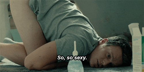 Man in a T-shirt kneels with his head on the floor beside an enema bottle, captioned 'So, so sexy'