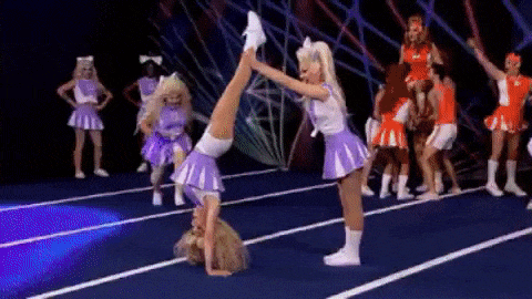 Queens in purple cheer uniforms perform a back walkover during their team routine
