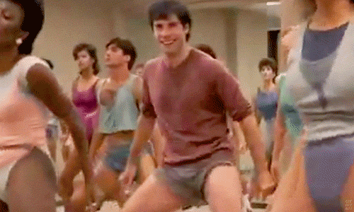 Group dancing through a high-energy 1980s aerobics routine in leotards and short shorts