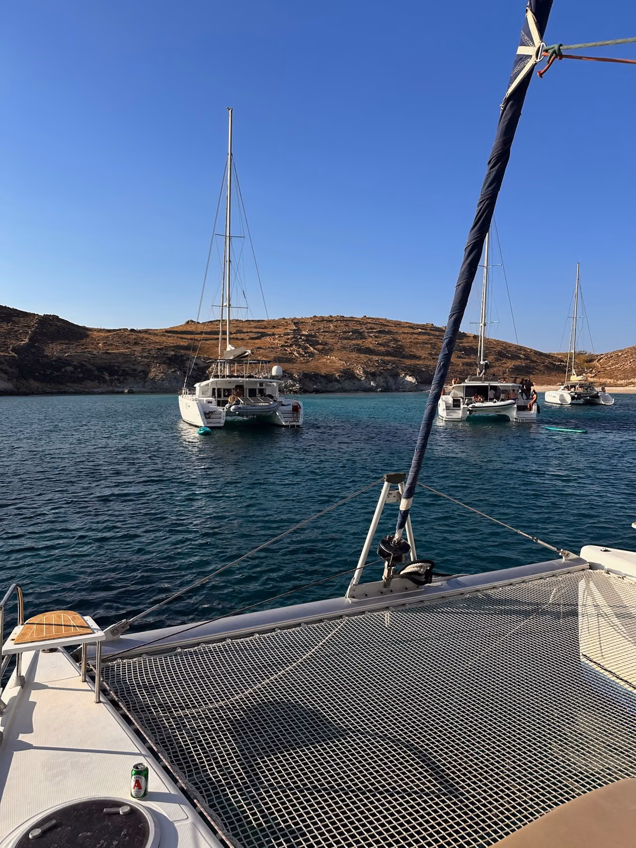 Yachts anchored in clear water off a rocky cove on Rhenia.