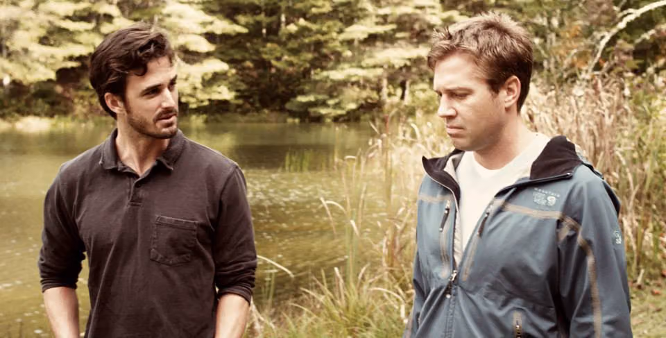 Two men talking beside a pond in a scene from Before the Fall, the gay Pride and Prejudice retelling