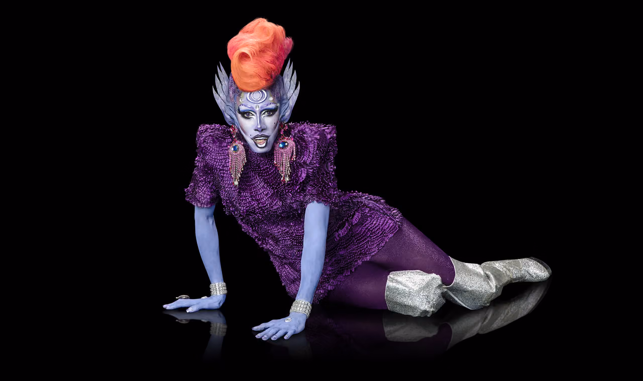 Nina Bo'nina Brown in blue body paint, an orange wig and a purple ruffled dress, eliminated after the lip sync