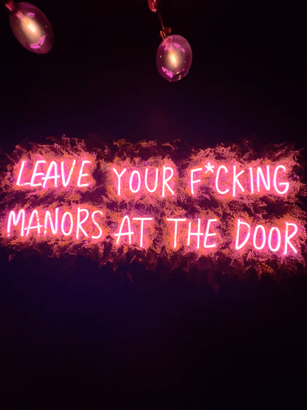 Pink neon sign reading “Leave your f*cking manors at the door” at NO Manors in Wilton Manors
