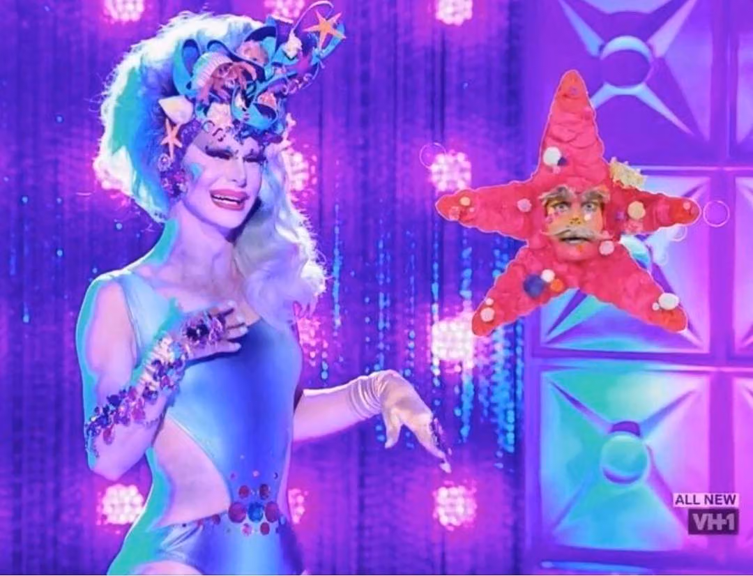Trinity the Tuck on the runway in a blue leotard and seashell headpiece beside her starfish sidekick, Stanky