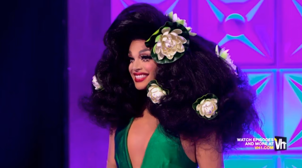 Valentina in a green gown and a huge black wig dotted with white water lilies on the season 9 runway