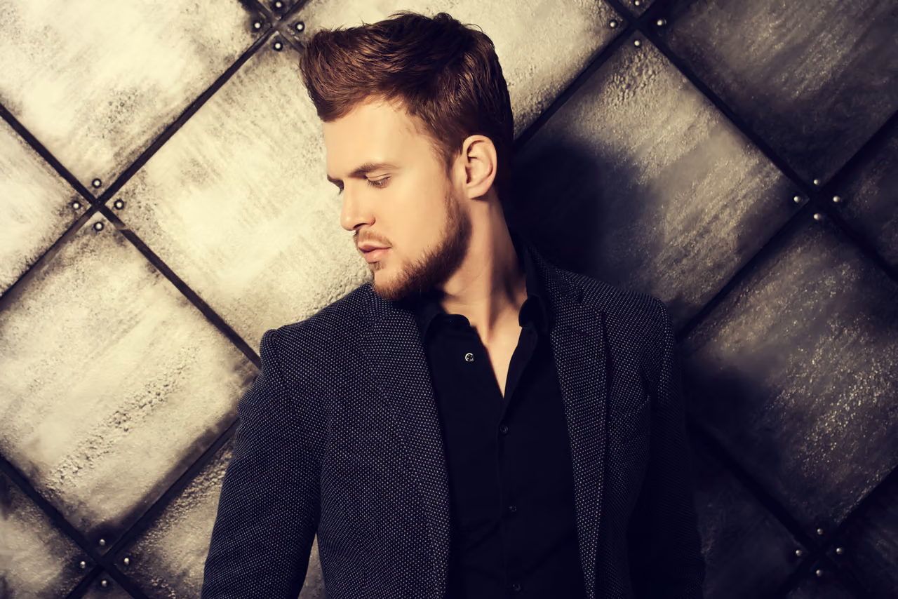 Bearded man with a styled quiff in a dark blazer and black shirt, a polished look for a profile picture