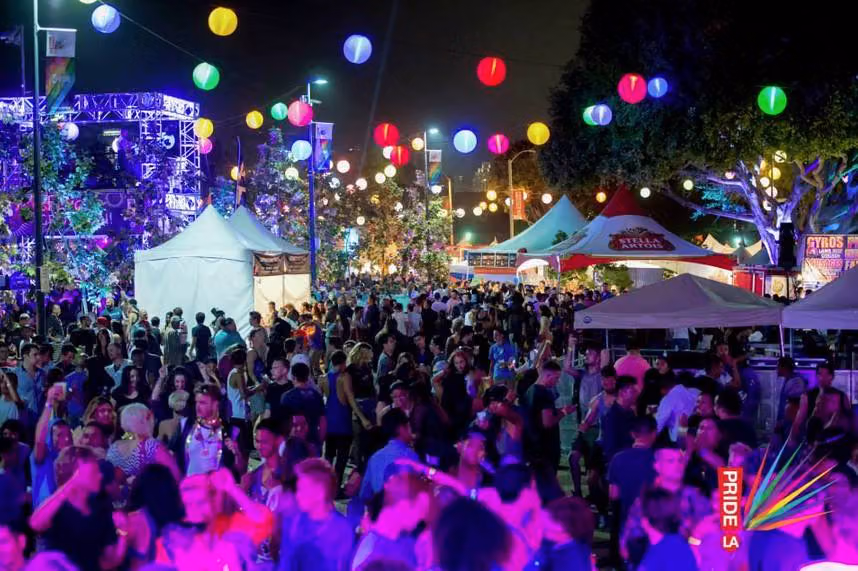 Crowds under glowing paper lanterns at a nighttime LA Pride street festival