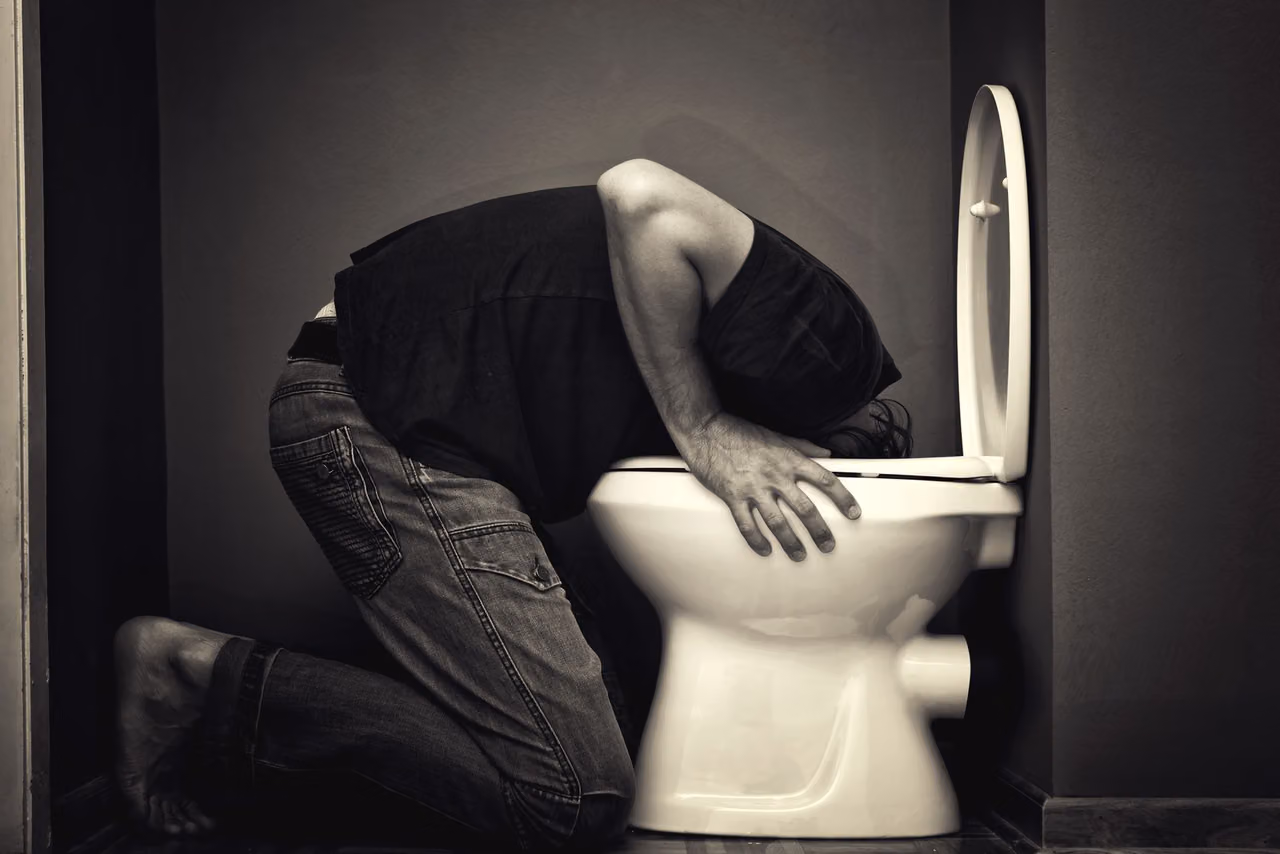 Man kneeling over a toilet with his head in the bowl, illustrating purging as an unsafe weight-loss method