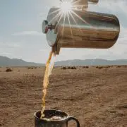 chrome coffee holder pouring coffee into a mug in the desert