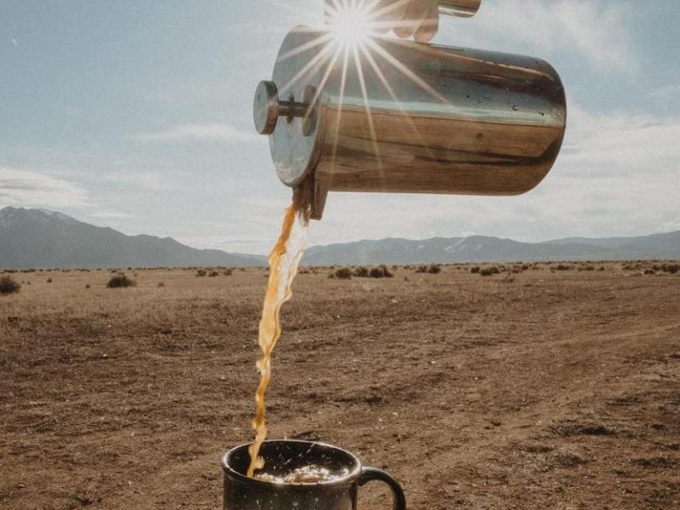chrome coffee holder pouring coffee into a mug in the desert