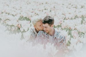 image of gay couple kissing in a field of flowers