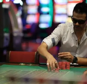 man gambling at poker table in white shirt