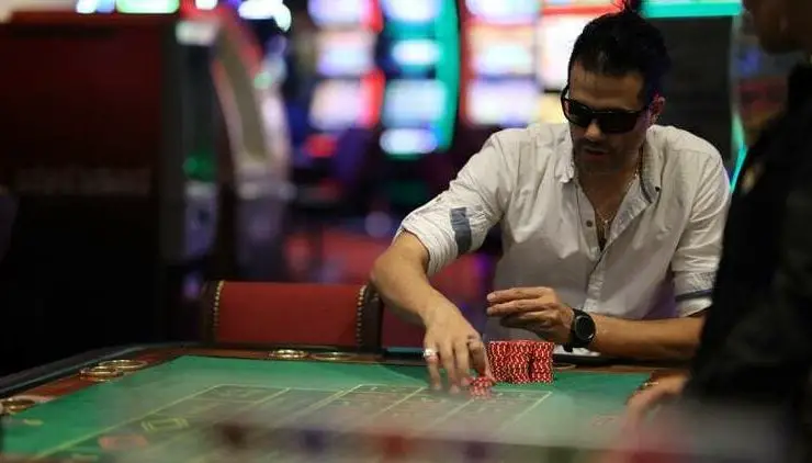 man gambling at poker table in white shirt