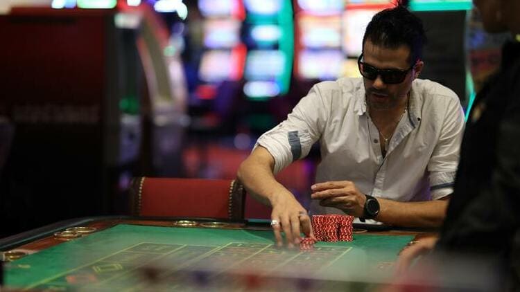 man gambling at poker table in white shirt