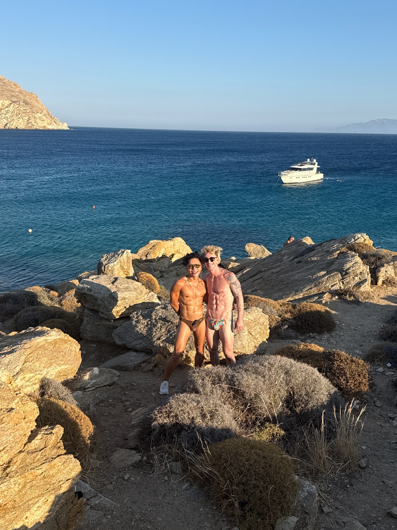 Mark and Beatus together on the rocks beside the blue sea at Elia Beach.
