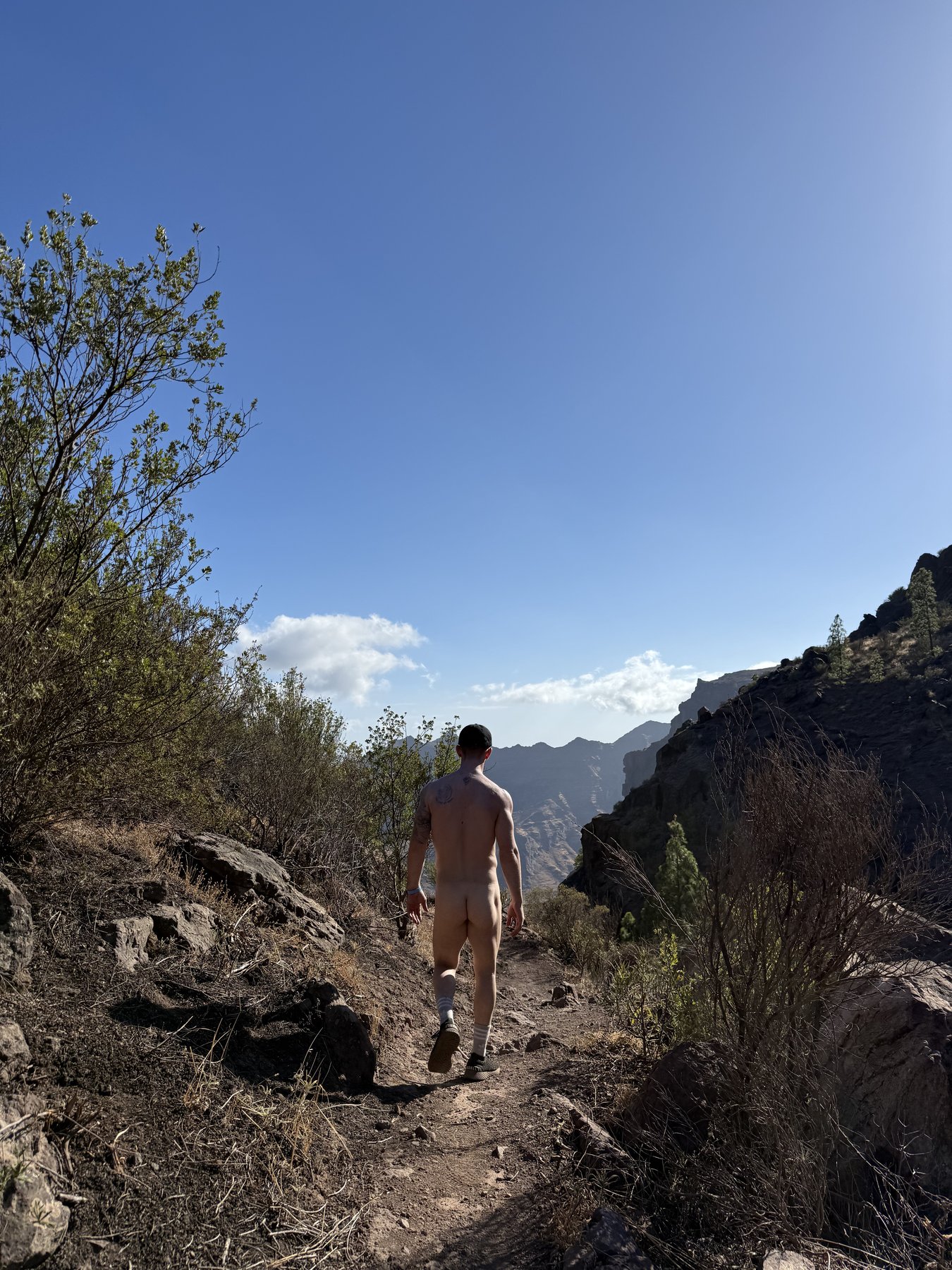 Mark walking away along a rocky mountain path, photographed from behind.