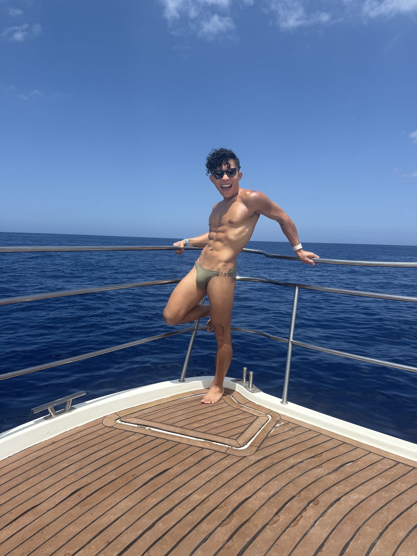 Beatus in swimwear at the bow of the yacht against the blue sea.