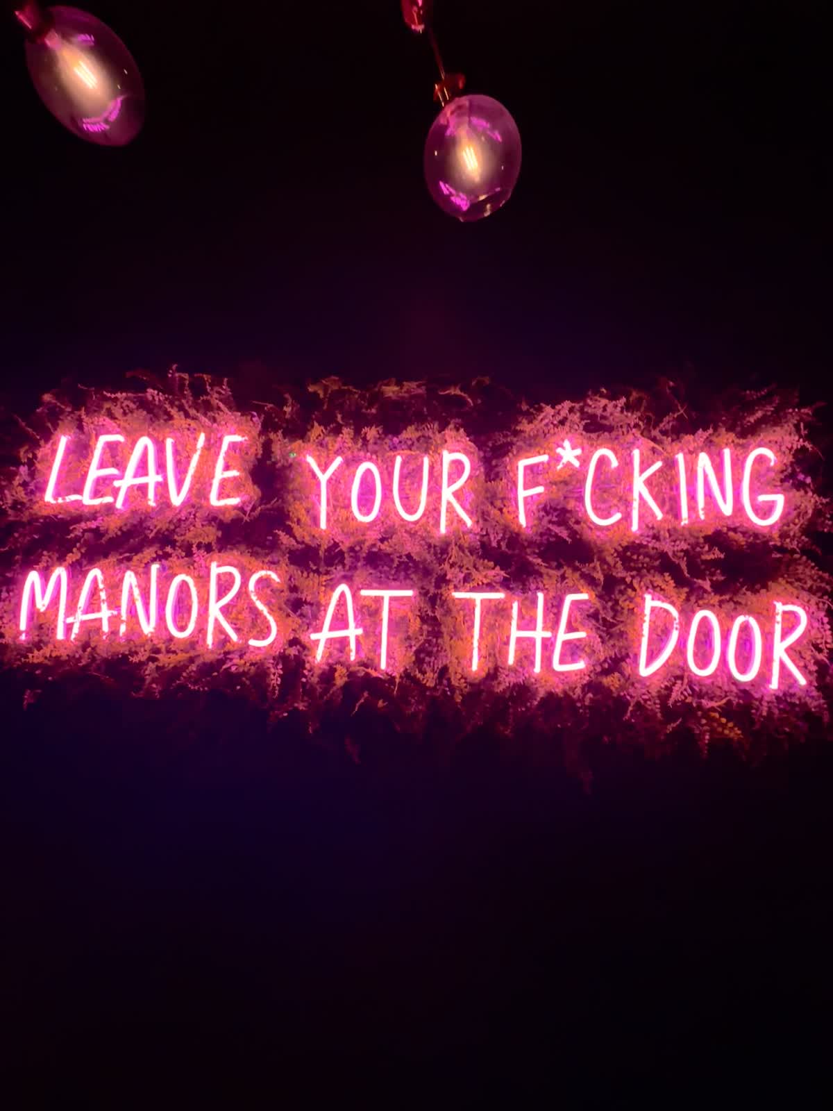 Pink neon sign reading “Leave your f*cking manors at the door” at NO Manors in Wilton Manors
