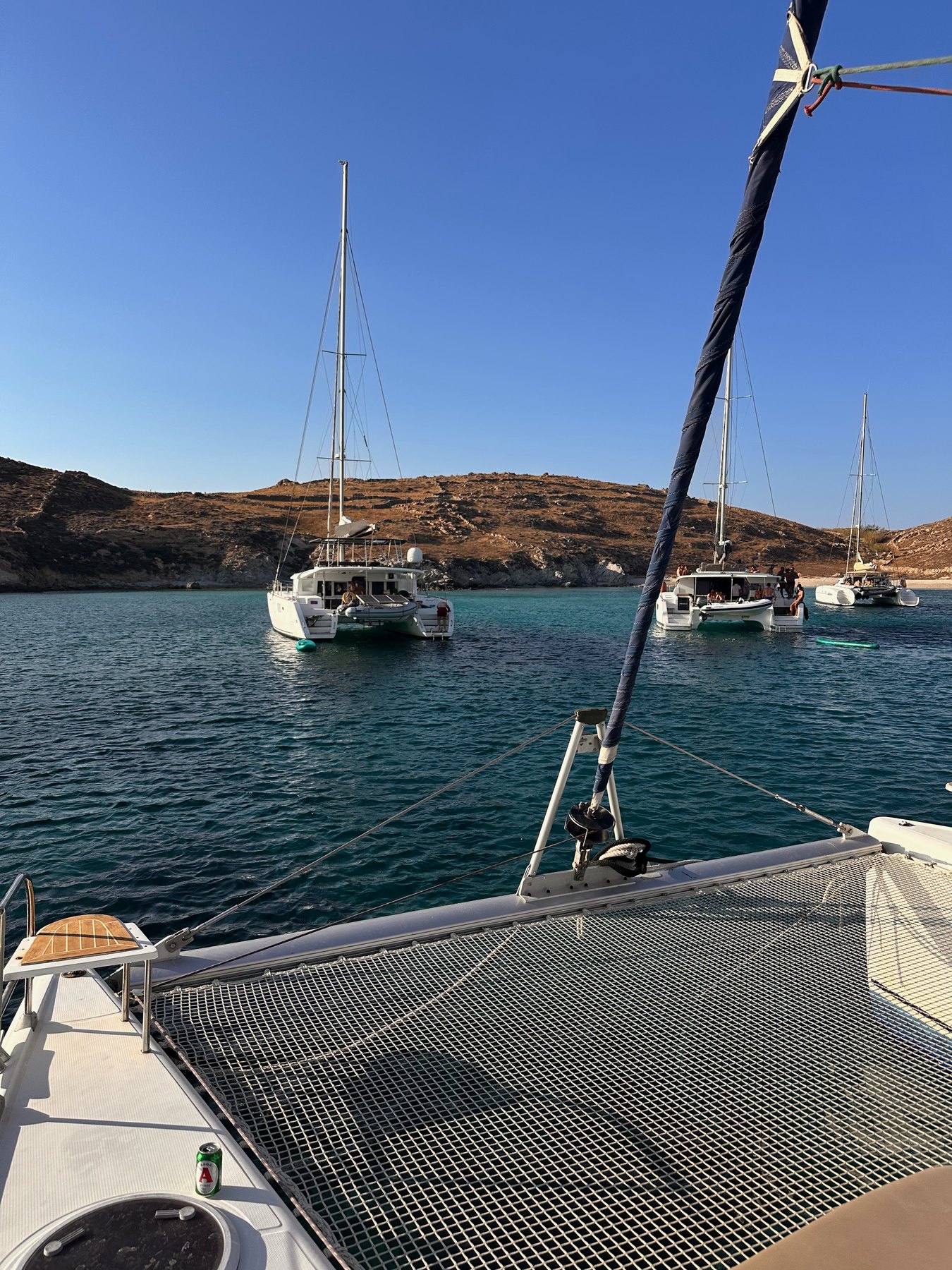 Yachts anchored in clear water off a rocky cove on Rhenia.