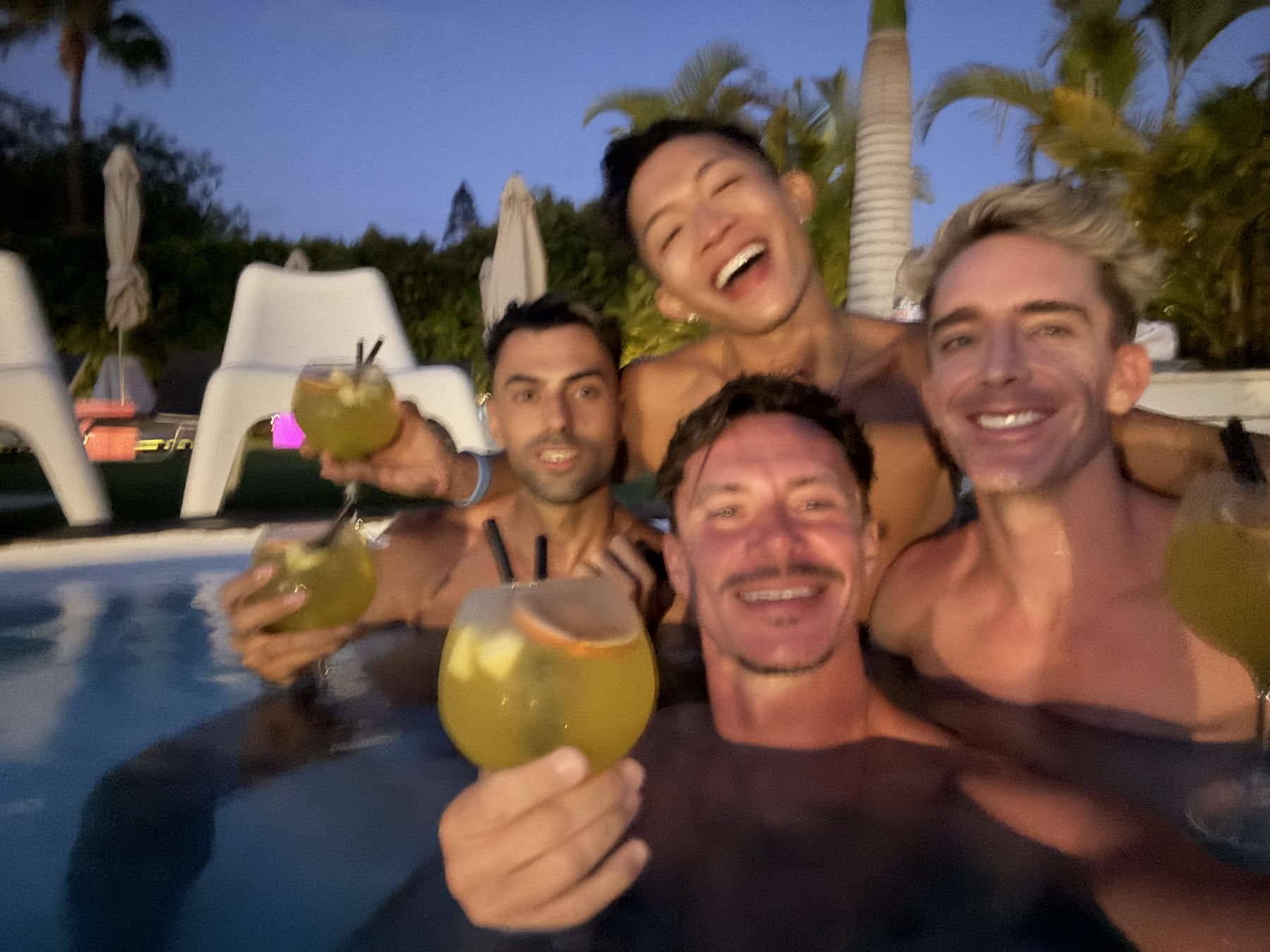 Mark and Beatus with friends and drinks in a swimming pool.